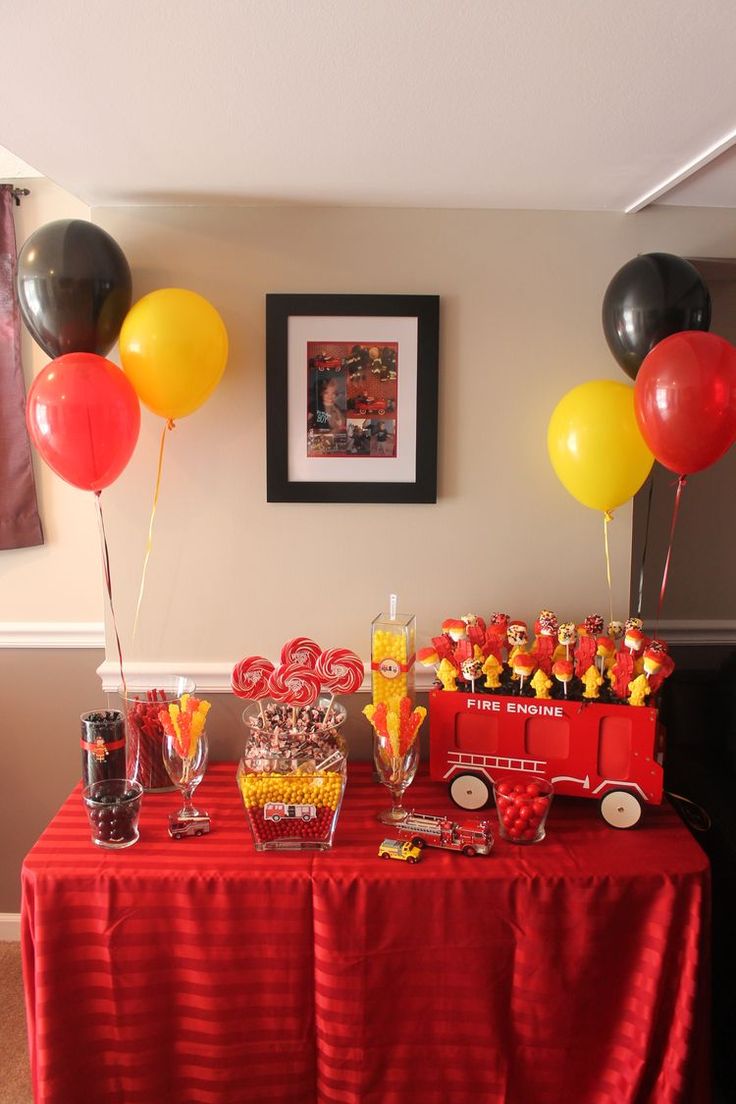 a table with balloons, candy and candies on it in front of a firetruck