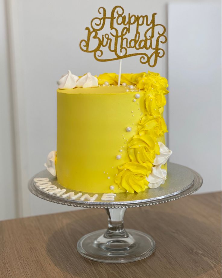 a yellow birthday cake with white frosting and flowers