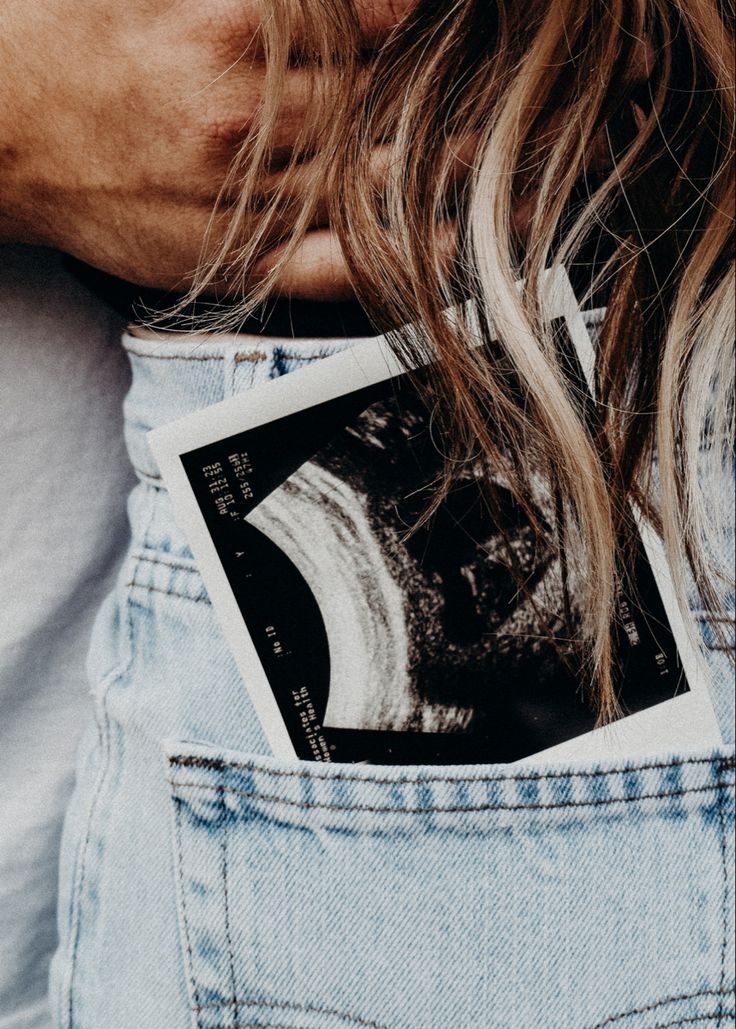 a person with long hair wearing blue jeans and holding money in their back pocket, close up