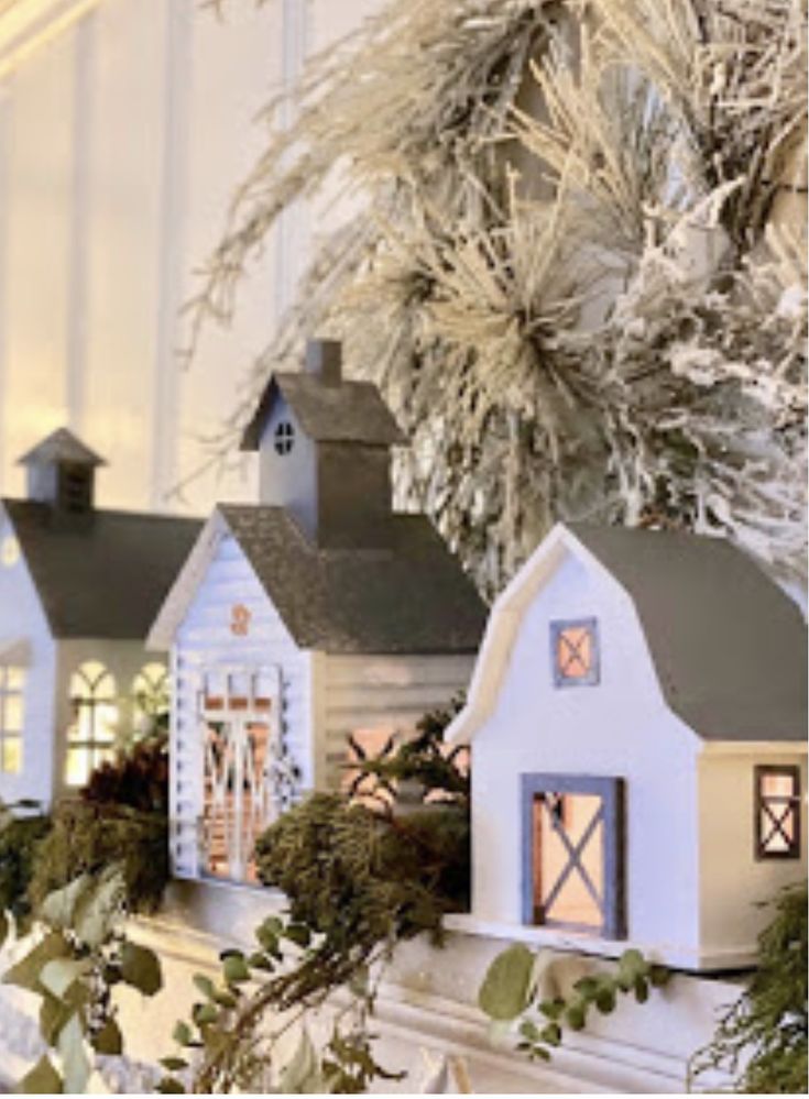 christmas decorations are displayed on the mantle in front of a white house and evergreen branches