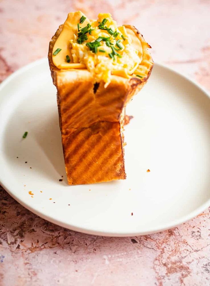 a piece of food on a white plate with green garnish and some parsley