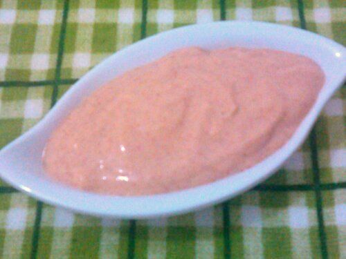 a white bowl filled with pink dip on top of a green and white checkered table cloth