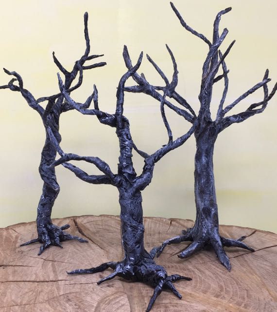 three metal trees sitting on top of a wooden table