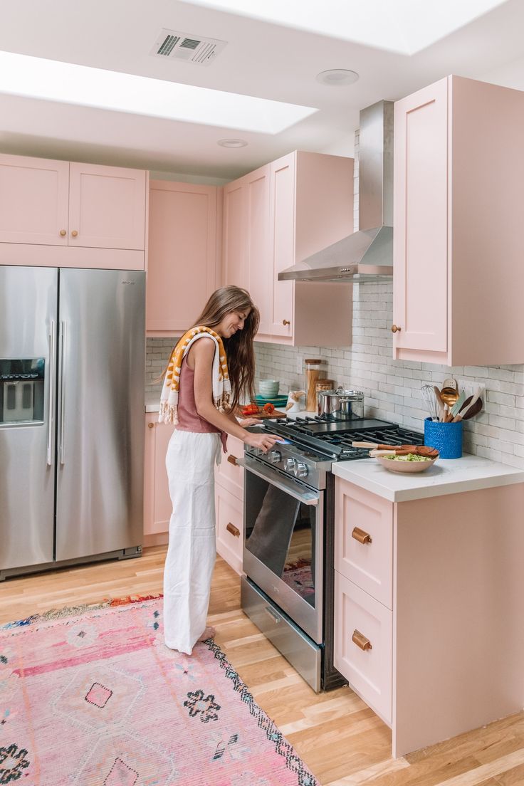 a woman standing in a kitchen preparing food on top of an oven and stovetop