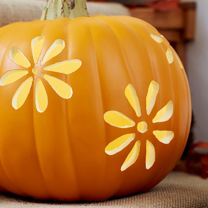 an orange pumpkin with yellow flowers painted on it