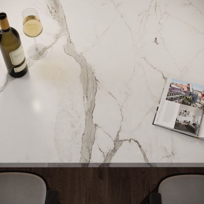 a marble table with two wine glasses and a magazine on it next to a bottle of wine