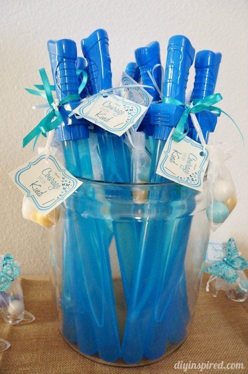 blue toothbrushes are in a clear glass container with tags on the top and bottom