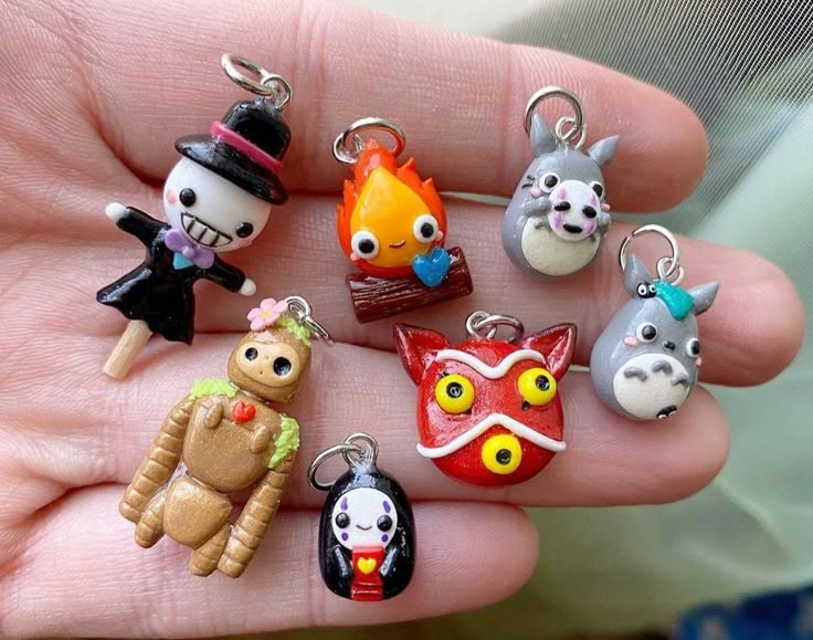 a hand holding a bunch of small key chains in it's palm, with different designs on them