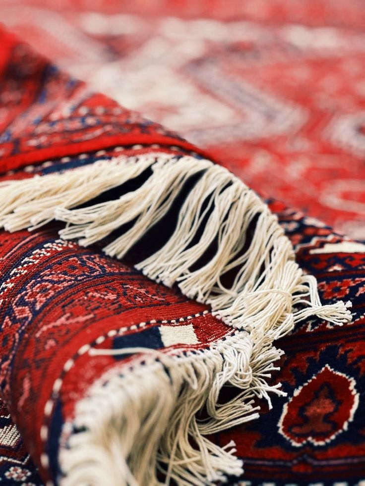 a red and blue rug with fringes laying on top of it's sides