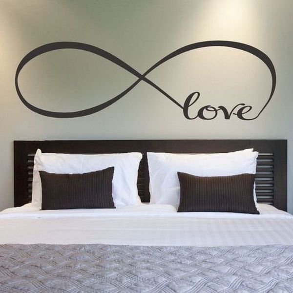 a bedroom with a large bed and love wall decal on the wall above it