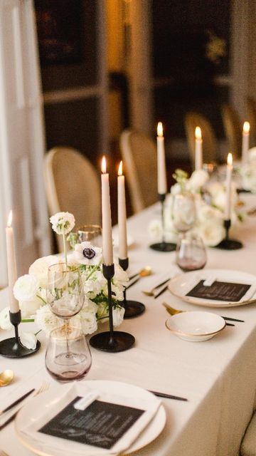 the table is set with white flowers and black place settings for dinner guests to enjoy