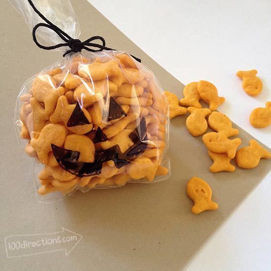 a plastic bag filled with halloween treats on top of a counter next to cut up cookies