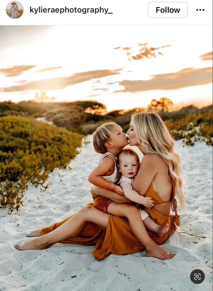 two women and a baby are sitting on the sand