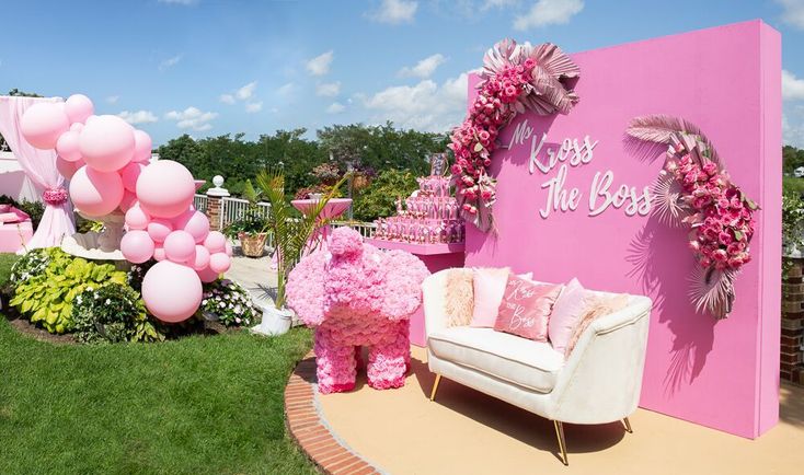 a room with pink decorations and balloons on the walls, including a white couch in front of a pink sign that says kiss the boss