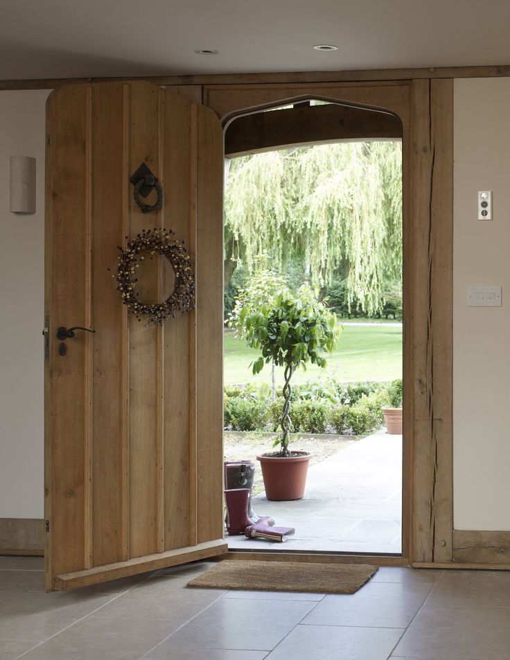 an open wooden door leading to a large patio area with potted plants on the floor