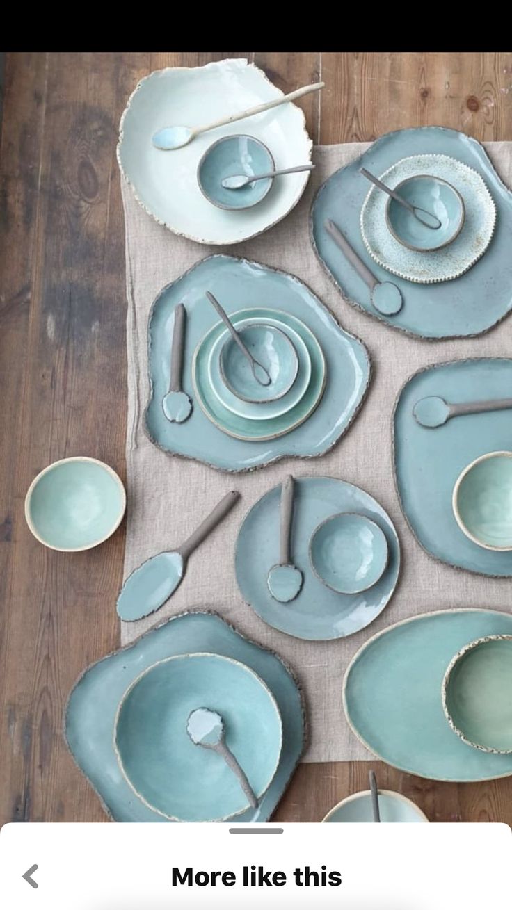 the table is set with blue dishes and silver utensils, which are on top of a beige placemat