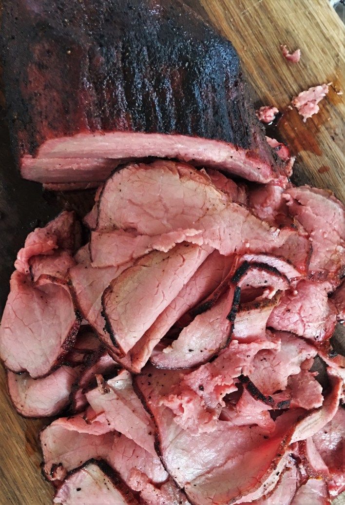 sliced meat sitting on top of a wooden cutting board