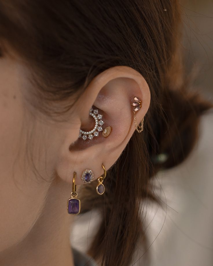 a close up of a person with ear piercings and an earring in the shape of a moon