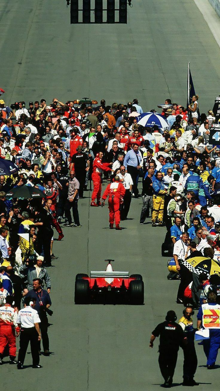 a group of people standing around a race car on a track in front of a crowd