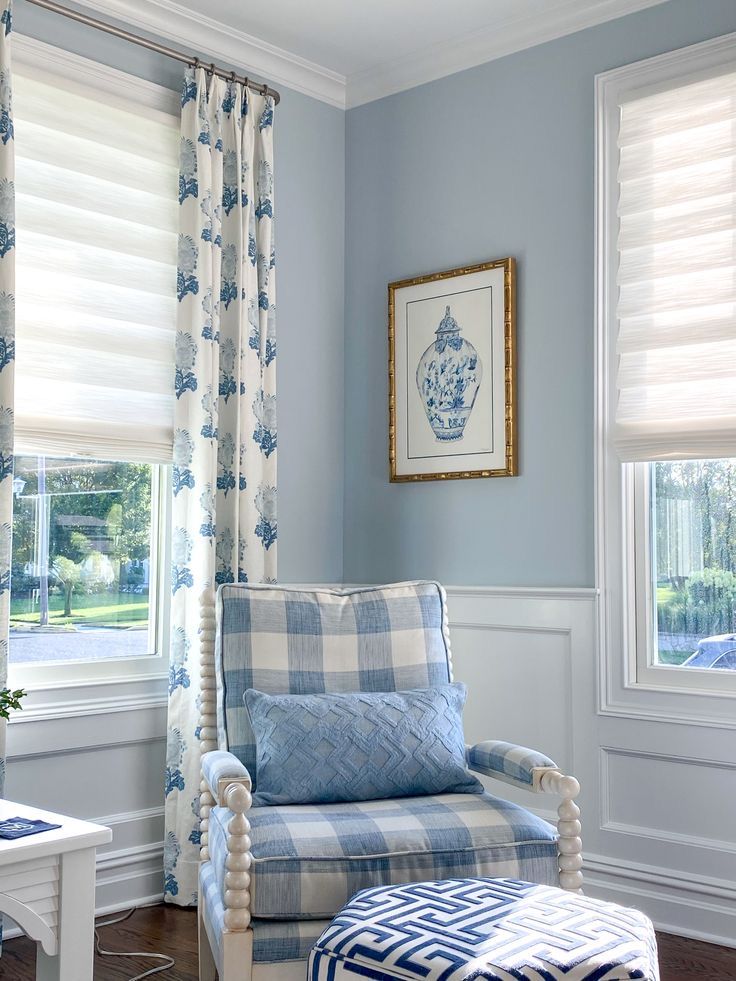 a chair and ottoman in a room with blue walls, white trim and window curtains