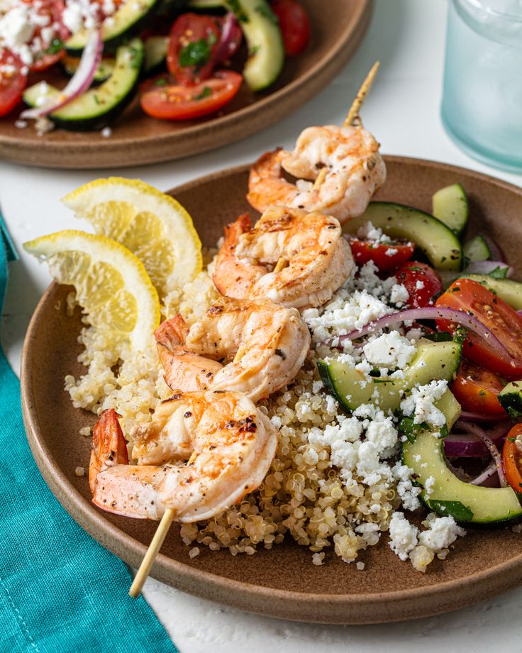 two plates filled with shrimp, rice and veggies on top of a table