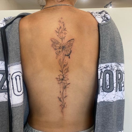 the back of a woman's neck with a flower and butterfly tattoo on it