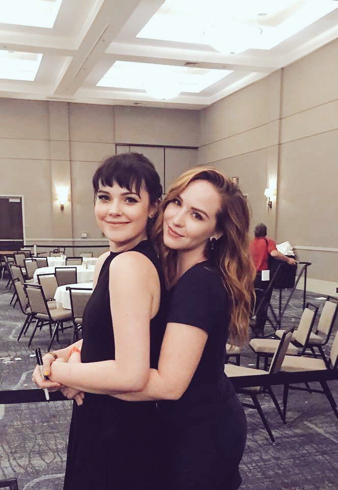 two young women standing next to each other in front of rows of tables and chairs