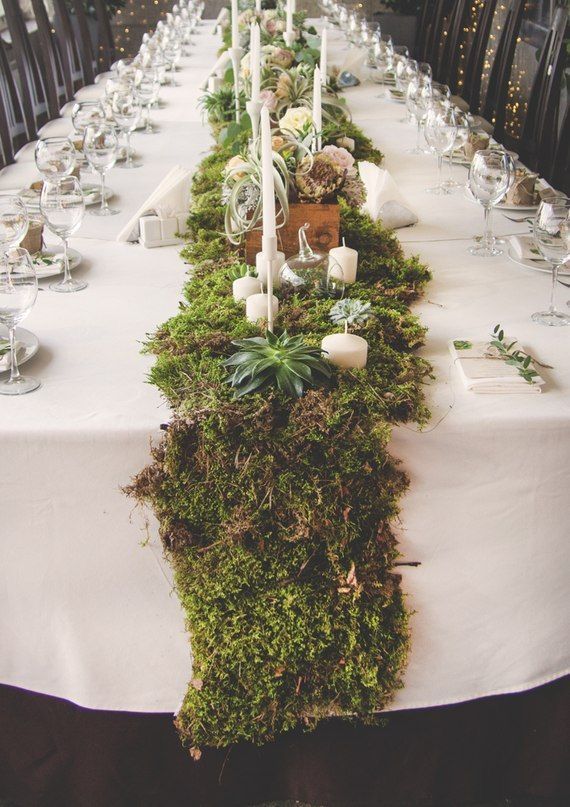 a long table covered in moss and candles