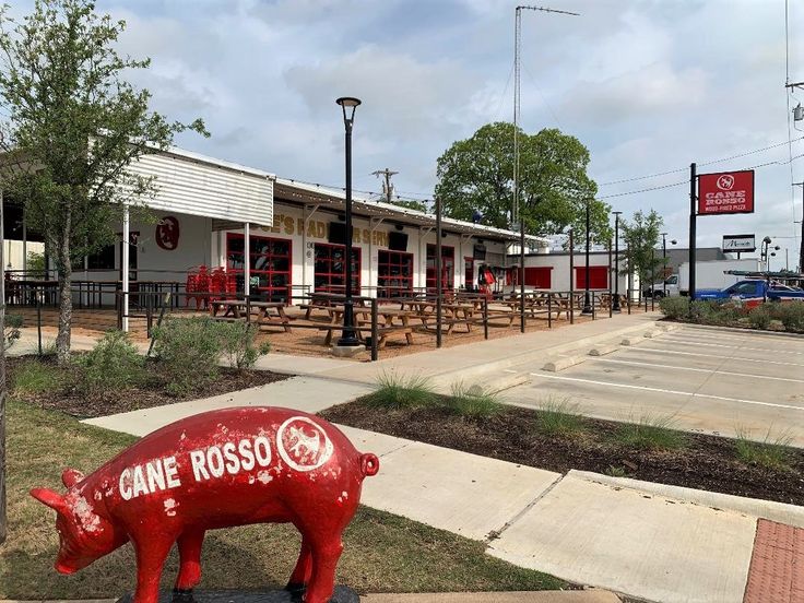 a red pig statue sitting in front of a restaurant