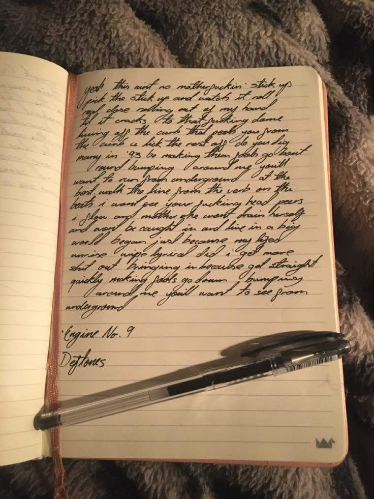 an open notebook with writing on it and a pen laying next to the book,