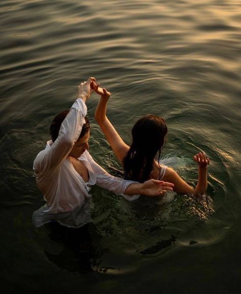 two people in the water holding hands and reaching for something with one hand while another reaches out