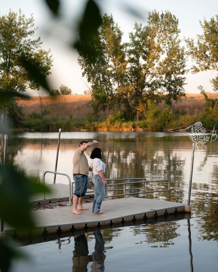 two people standing on a dock near the water