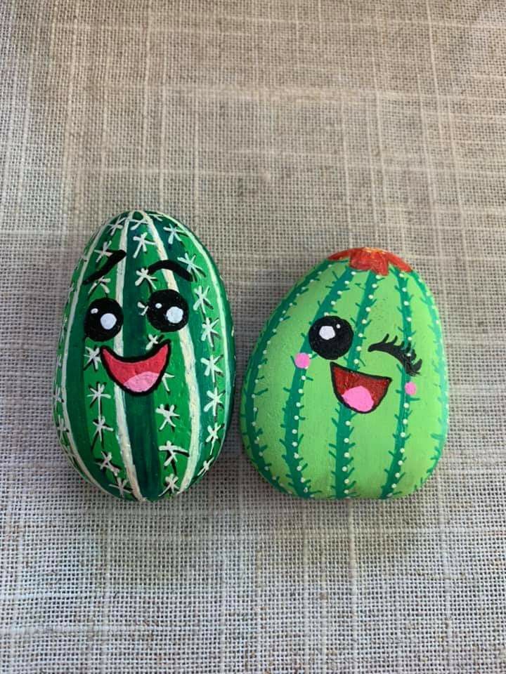 two painted rocks sitting on top of a cloth covered surface with faces drawn on them