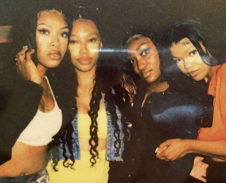 four women posing for a photo in front of a mirror