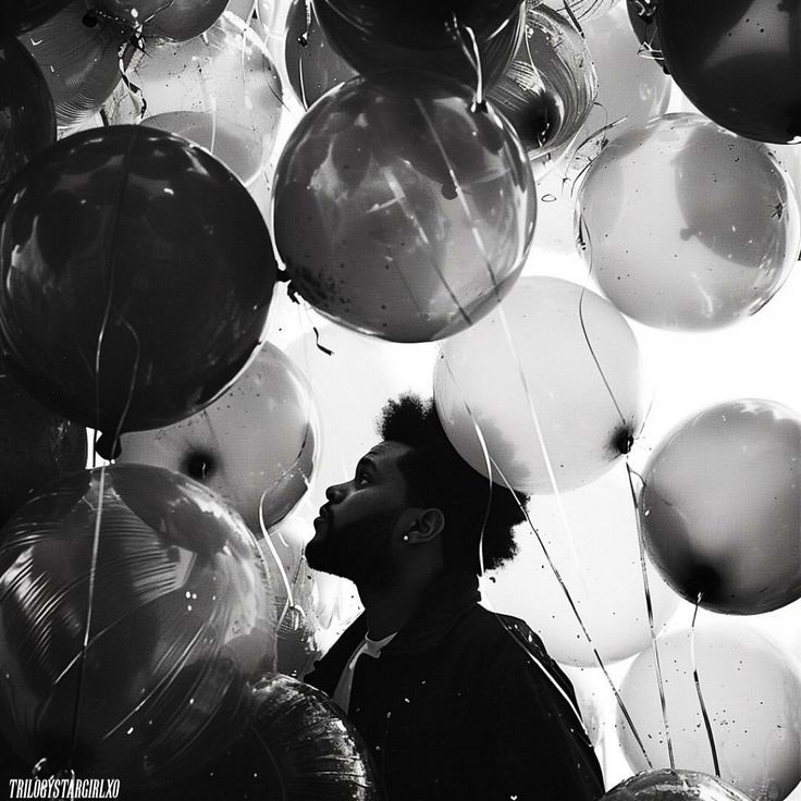 a man standing in front of a bunch of balloons