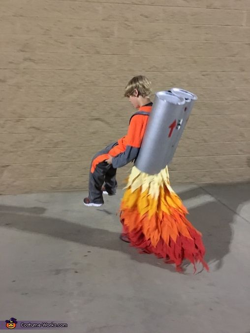 a boy in an orange and yellow costume carrying a fire hydrant on his back