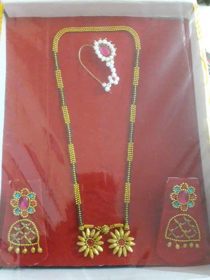 an assortment of necklaces and earrings are displayed in a red box on the table