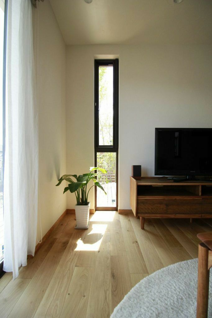 a living room with wooden floors and a television on top of a stand next to a window