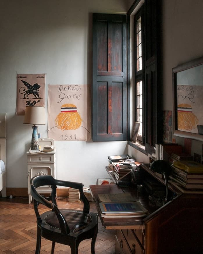 a bedroom with a bed, desk and chair next to an open window on the wall