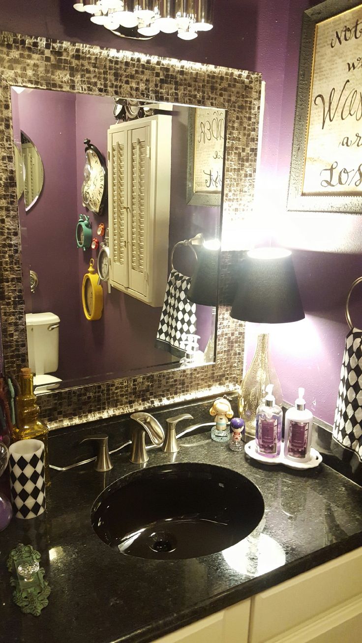 a bathroom sink sitting under a mirror next to a vanity with a black counter top