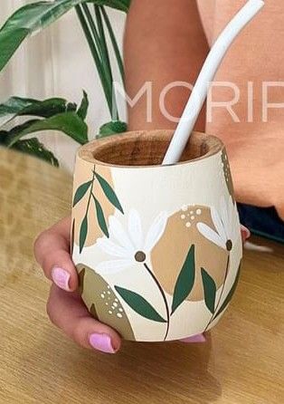 a woman holding a cup with a toothbrush in it on top of a wooden table