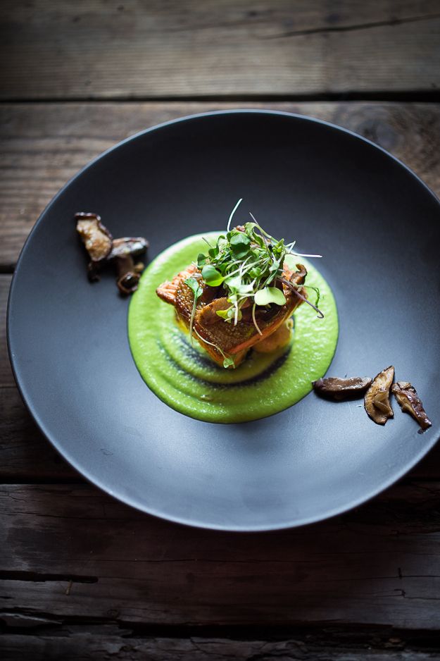 a black plate topped with food on top of a wooden table