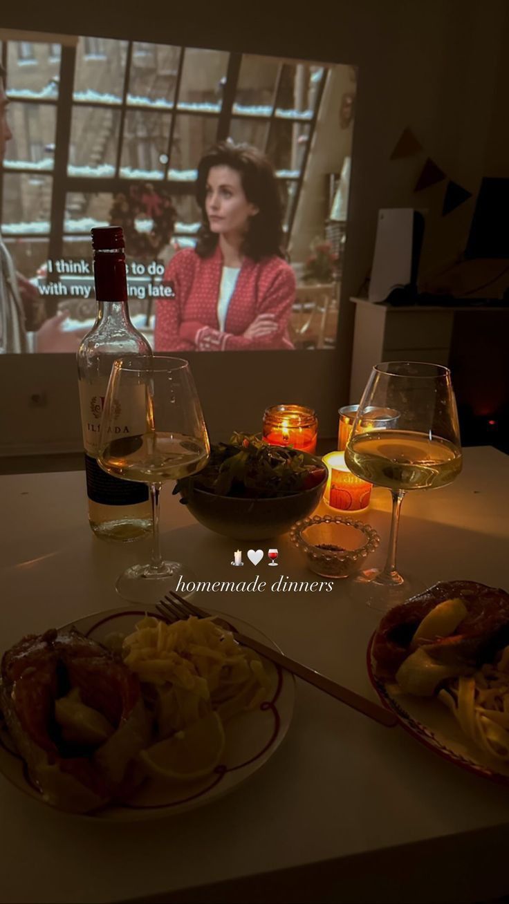 two plates with food and wine on a table in front of a television