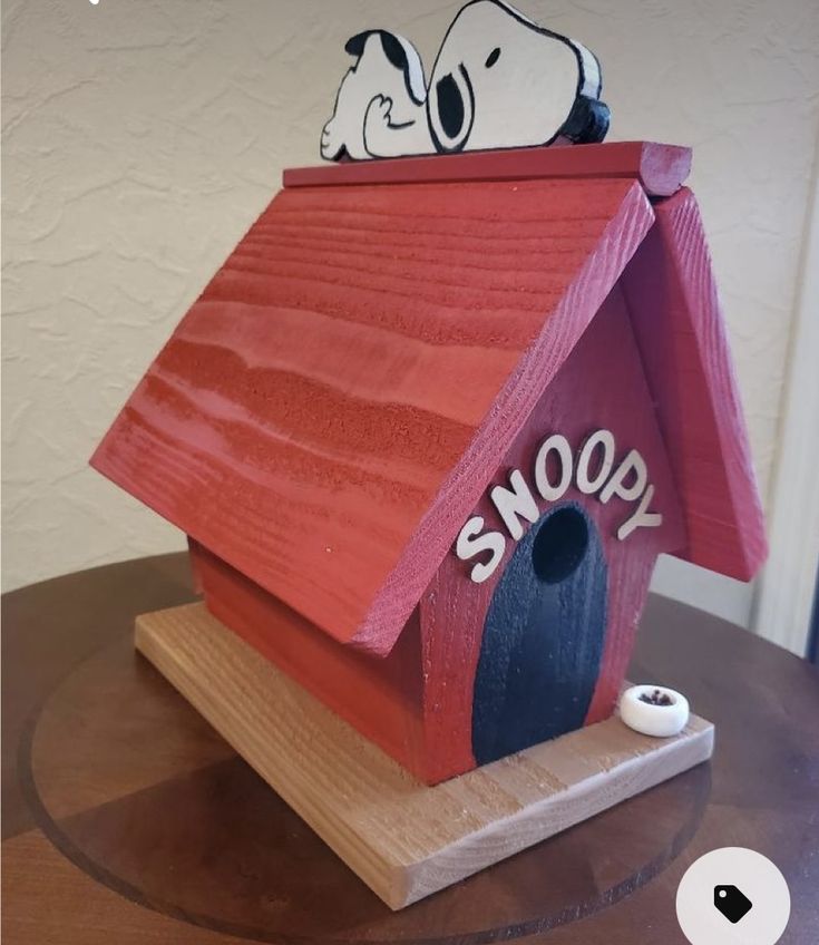 a wooden birdhouse with snoopy painted on it's roof and the word snoopy written in white