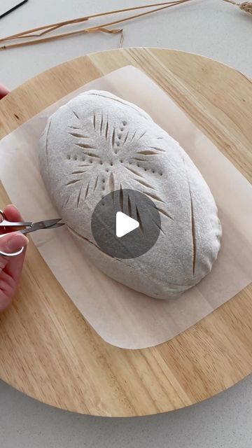 a person cutting up a piece of bread on top of a wooden board with scissors