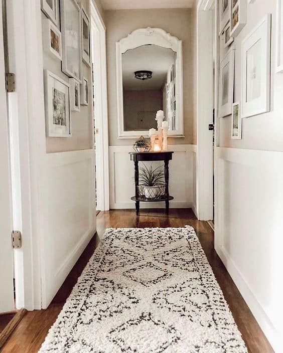 a hallway with pictures on the wall and a rug on the floor in front of it