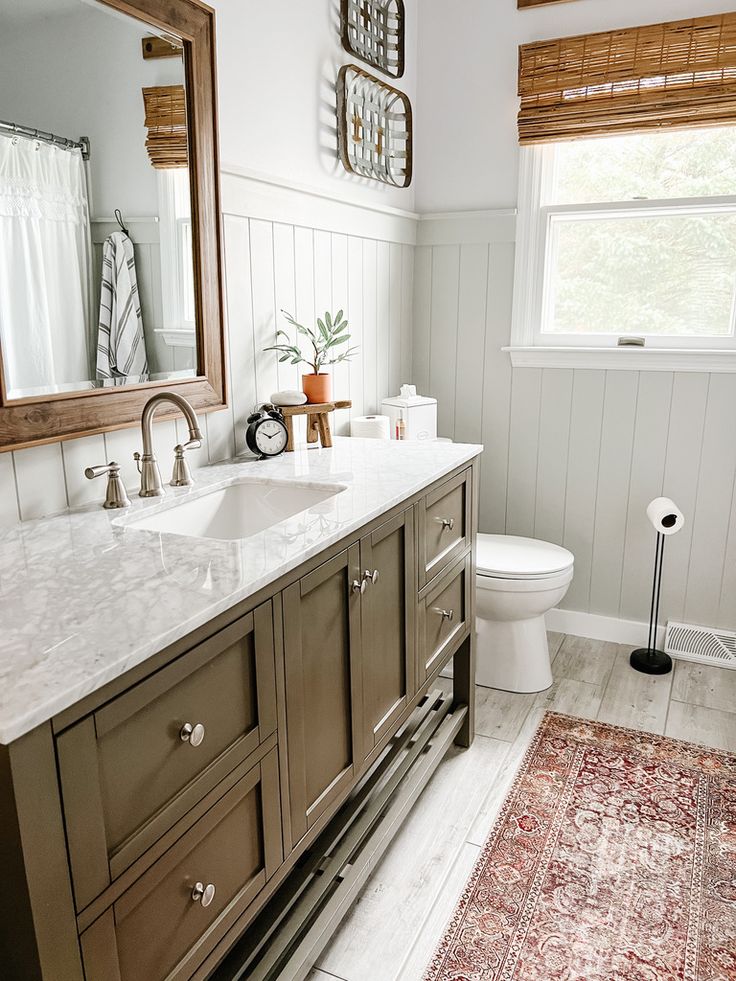 a bathroom with a sink, mirror and rug on the floor in front of it