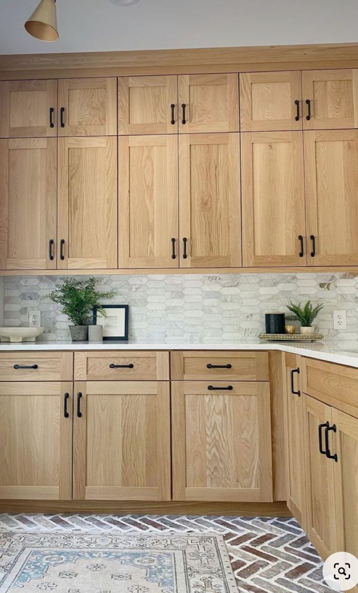 a kitchen filled with wooden cabinets and white counter tops next to a potted plant