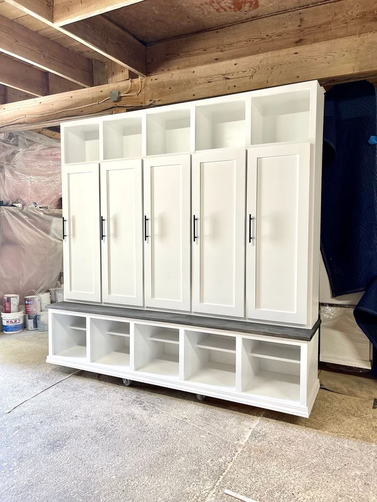 an unfinished garage with white cabinets and shelves