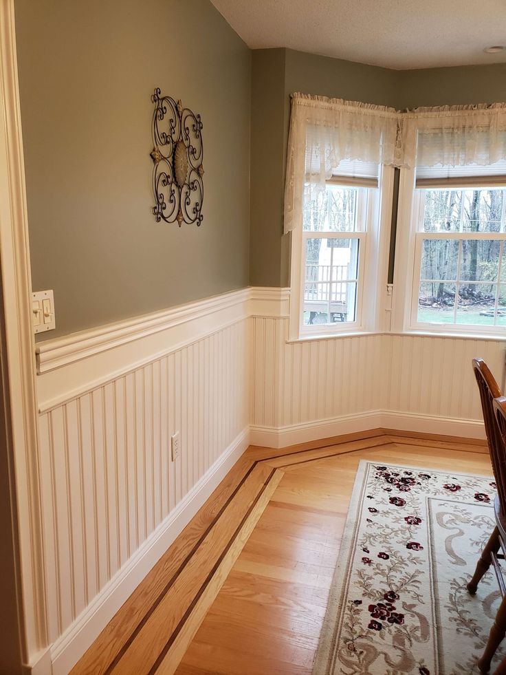 a dining room with hard wood floors and white wains on the wall, along with two windows